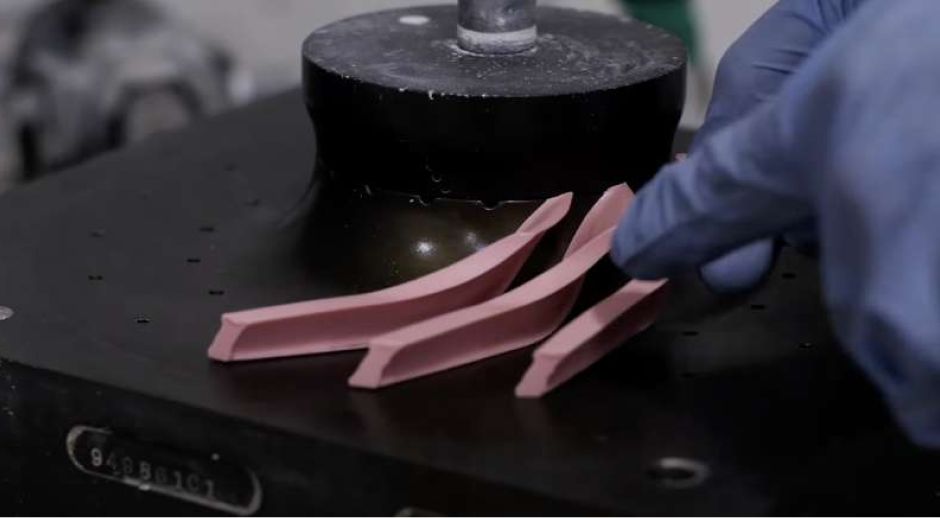 Gloved hand placing pink wax patterns used for investment casting.